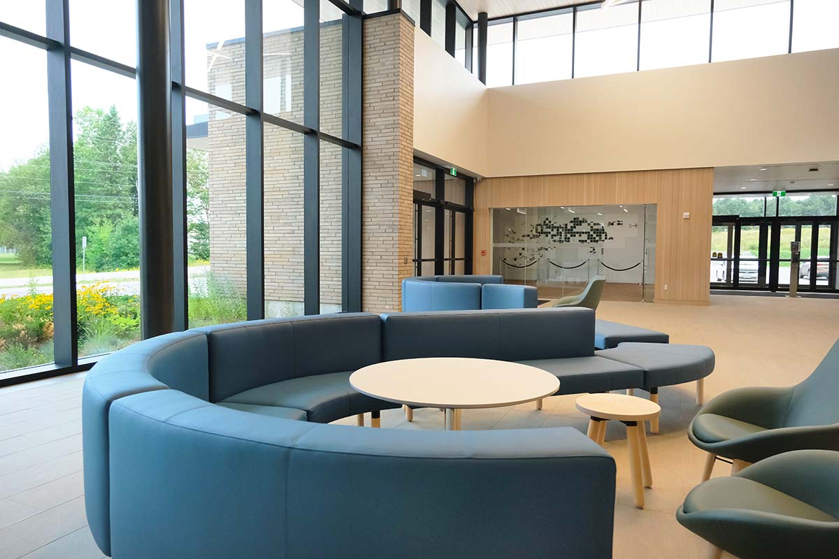 A living room with a couch , chairs , tables and a large window.