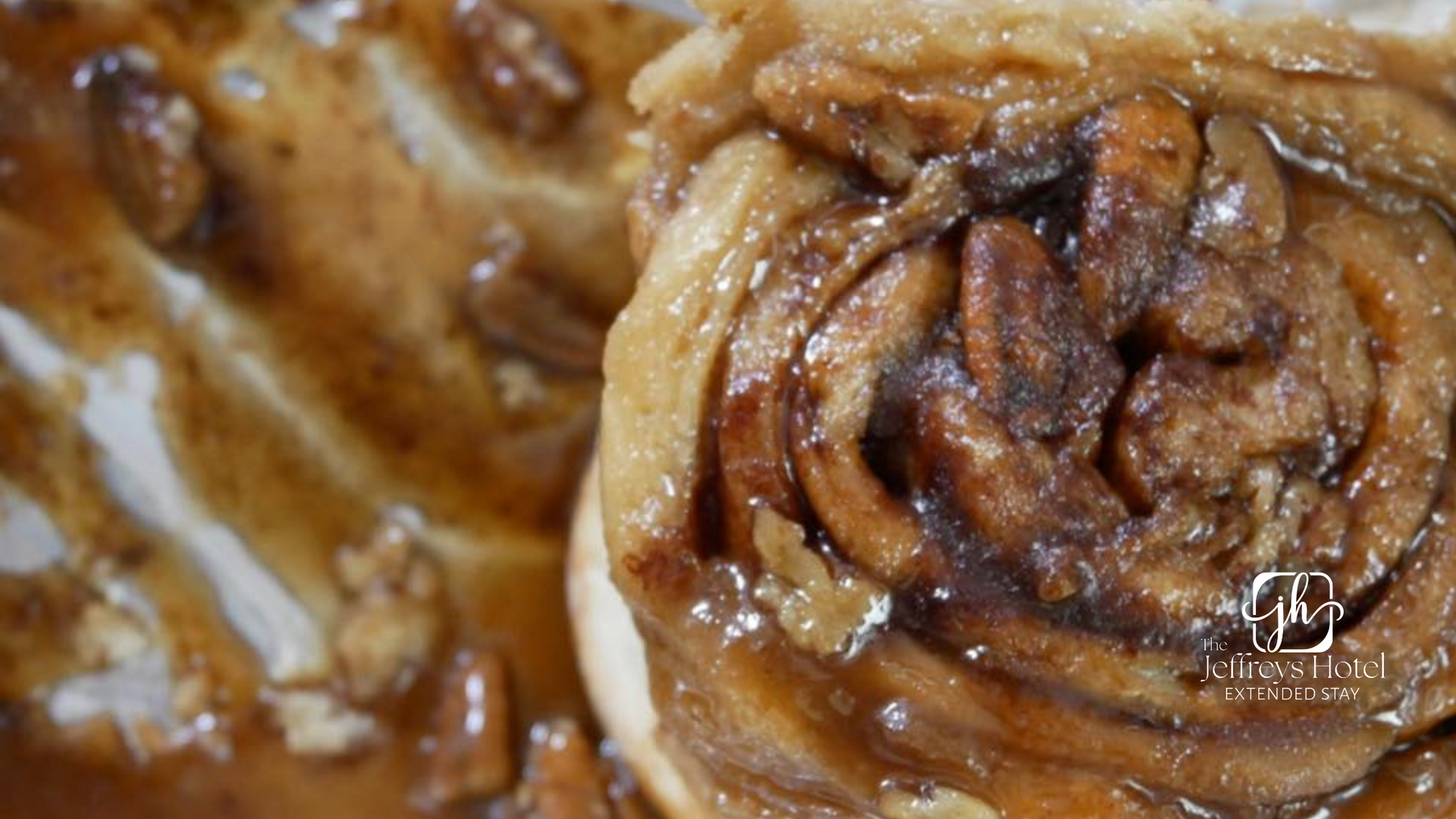 Close-up of a sticky, glazed cinnamon roll with visible layers and pecans in Osceola, Iowa.