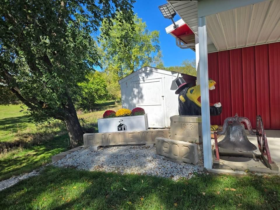 Outdoor display at Clarke County Historical Museum in Osceola, Iowa, featuring a schoolhouse sign, bell, and carved mascot