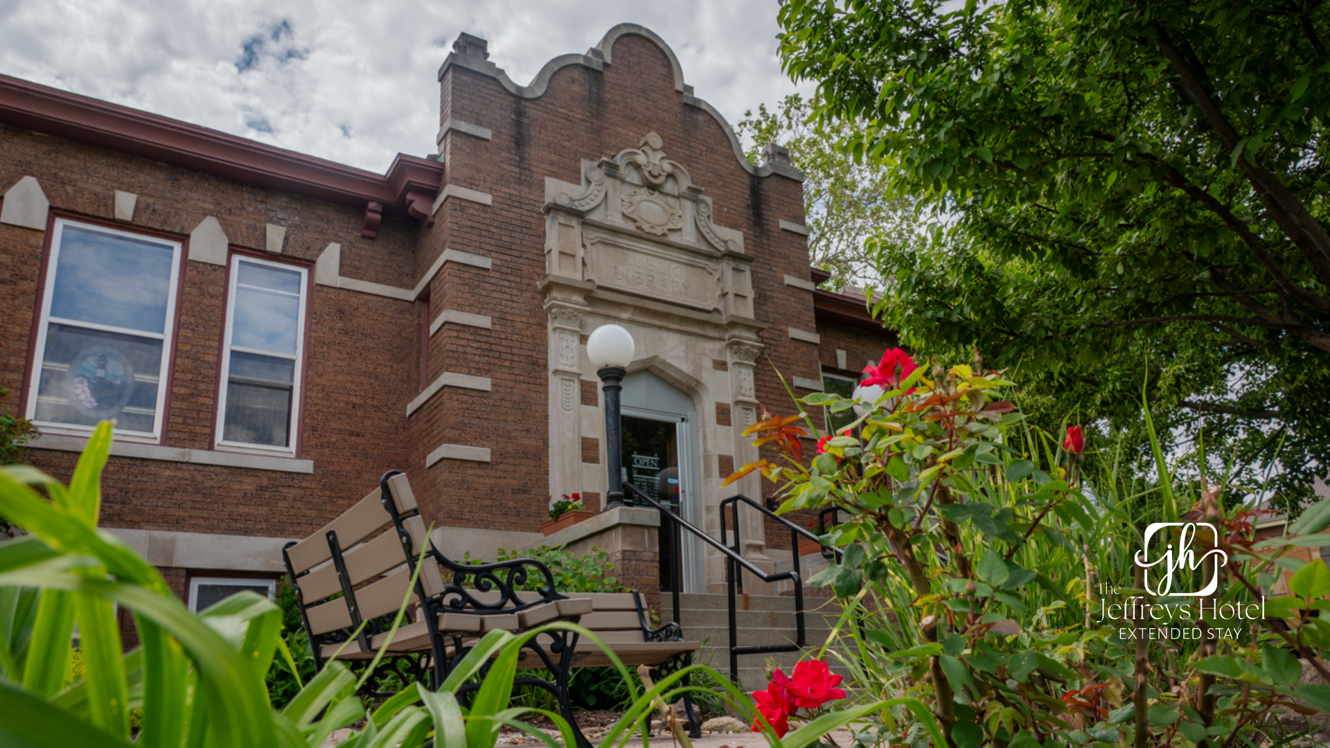 Osceola, Iowa Library...Brick building with arched entrance, windows, and floral foreground.