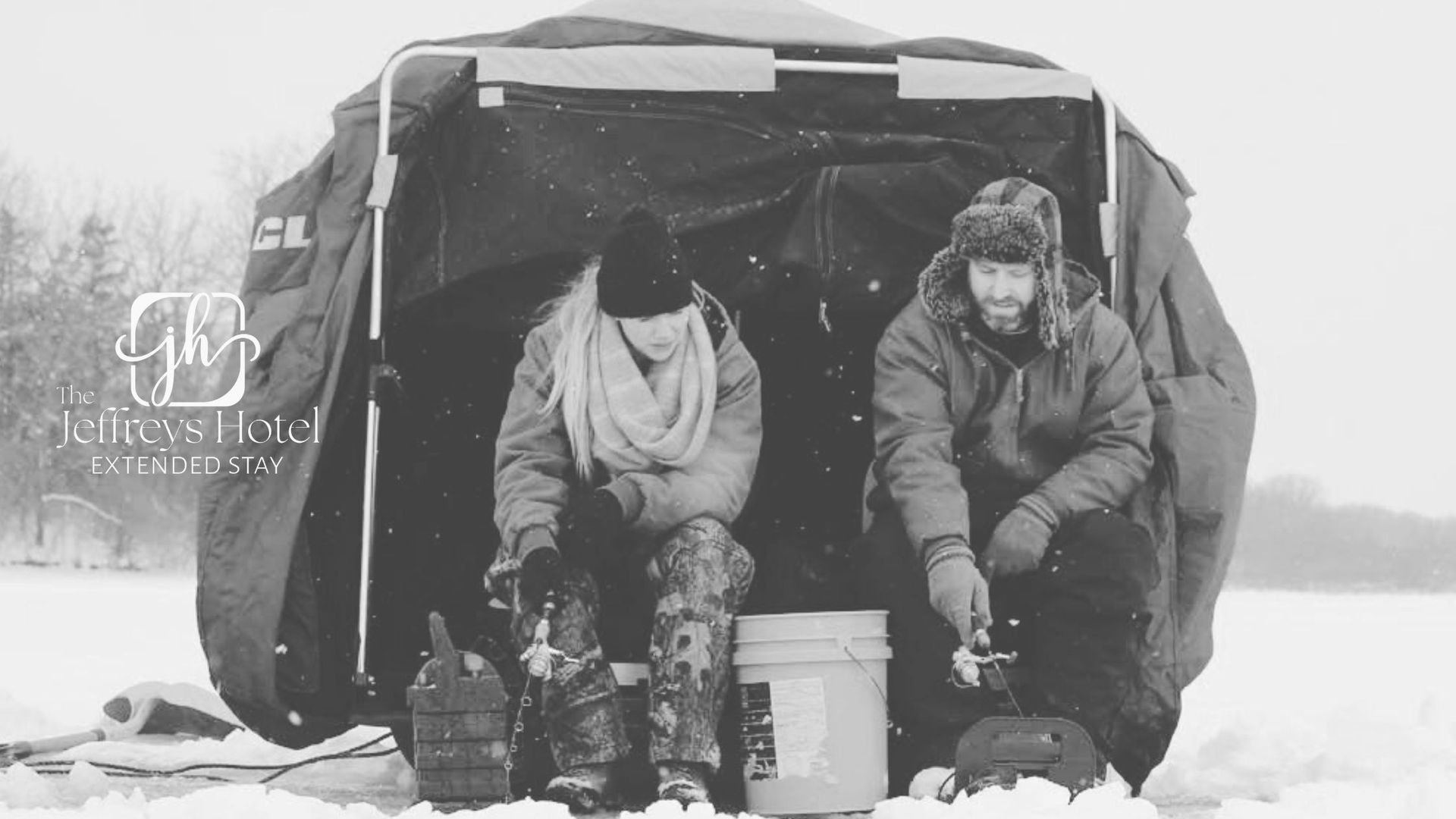 Two people ice fishing near Osceola, Iowa in a shelter on a snowy day.