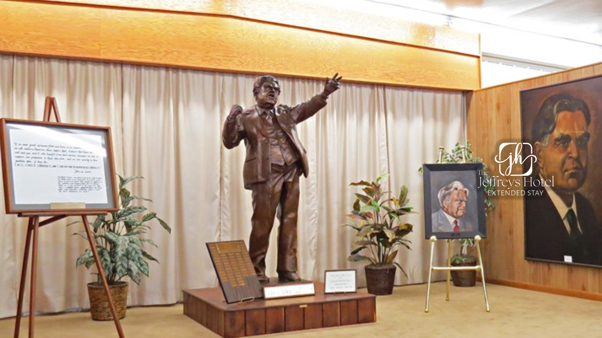 Bronze statue of a John L. Lewis with arms raised, in a room with portraits and text displays.