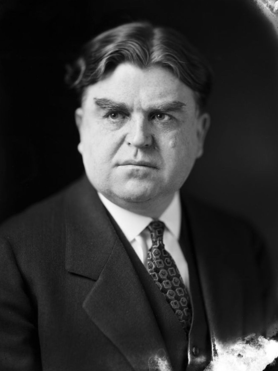 Portrait of a middle-aged man in a suit, looking directly at the viewer with a serious expression.