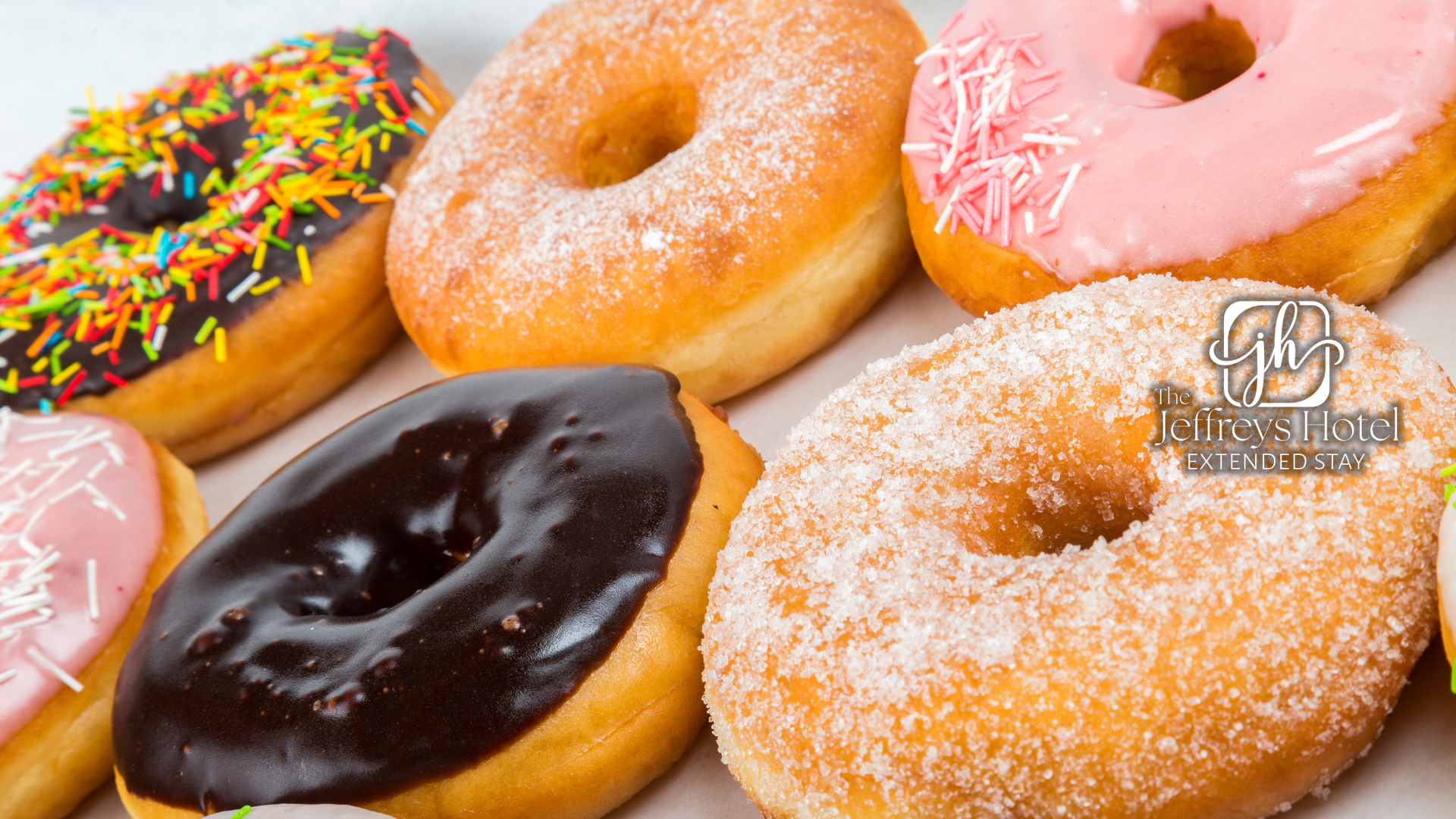 Assortment of donuts with various toppings and glazes, including sprinkles and sugar, arranged closely.