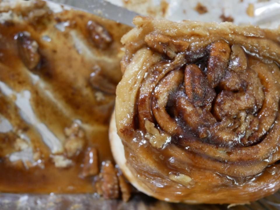 Close-up of a sticky pecan roll with gooey, caramelized topping and visible layers.