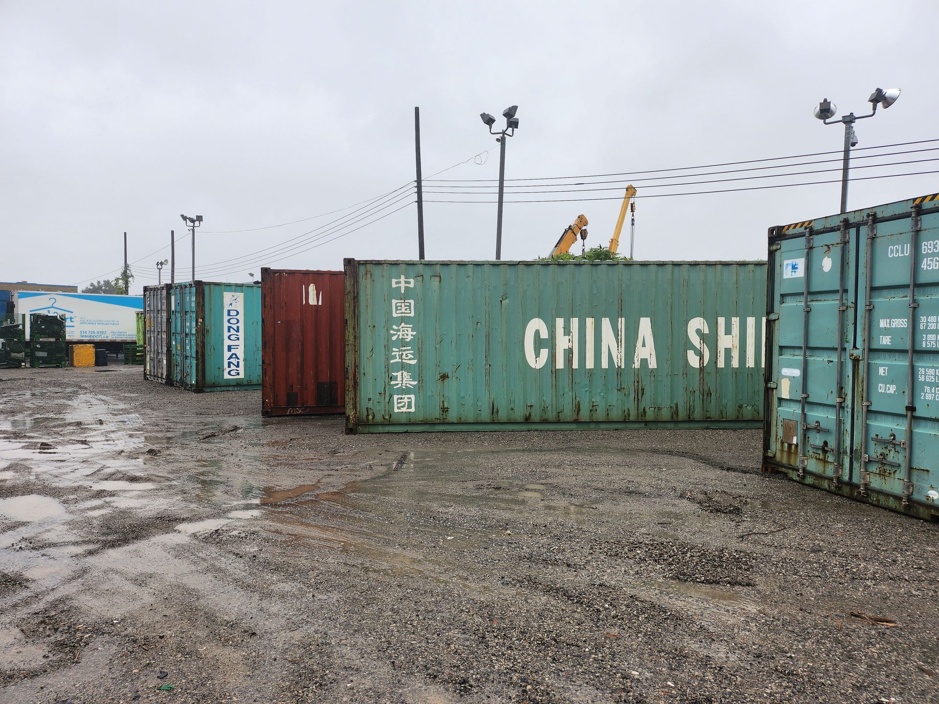 Une rangée de conteneurs d'expédition est alignée sur un terrain en terre.