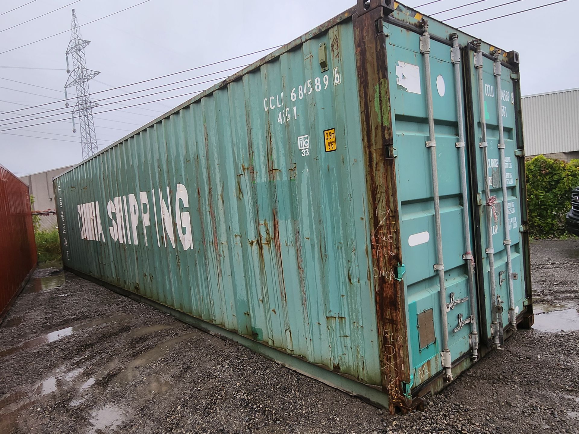 Un conteneur d'expédition vert se trouve sur un terrain vague.