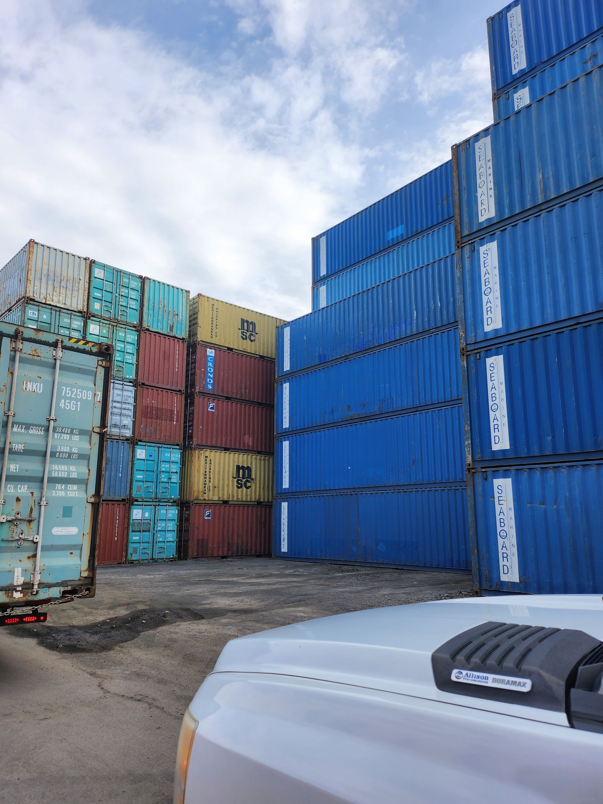 Un camion est garé devant une pile de conteneurs d'expédition.