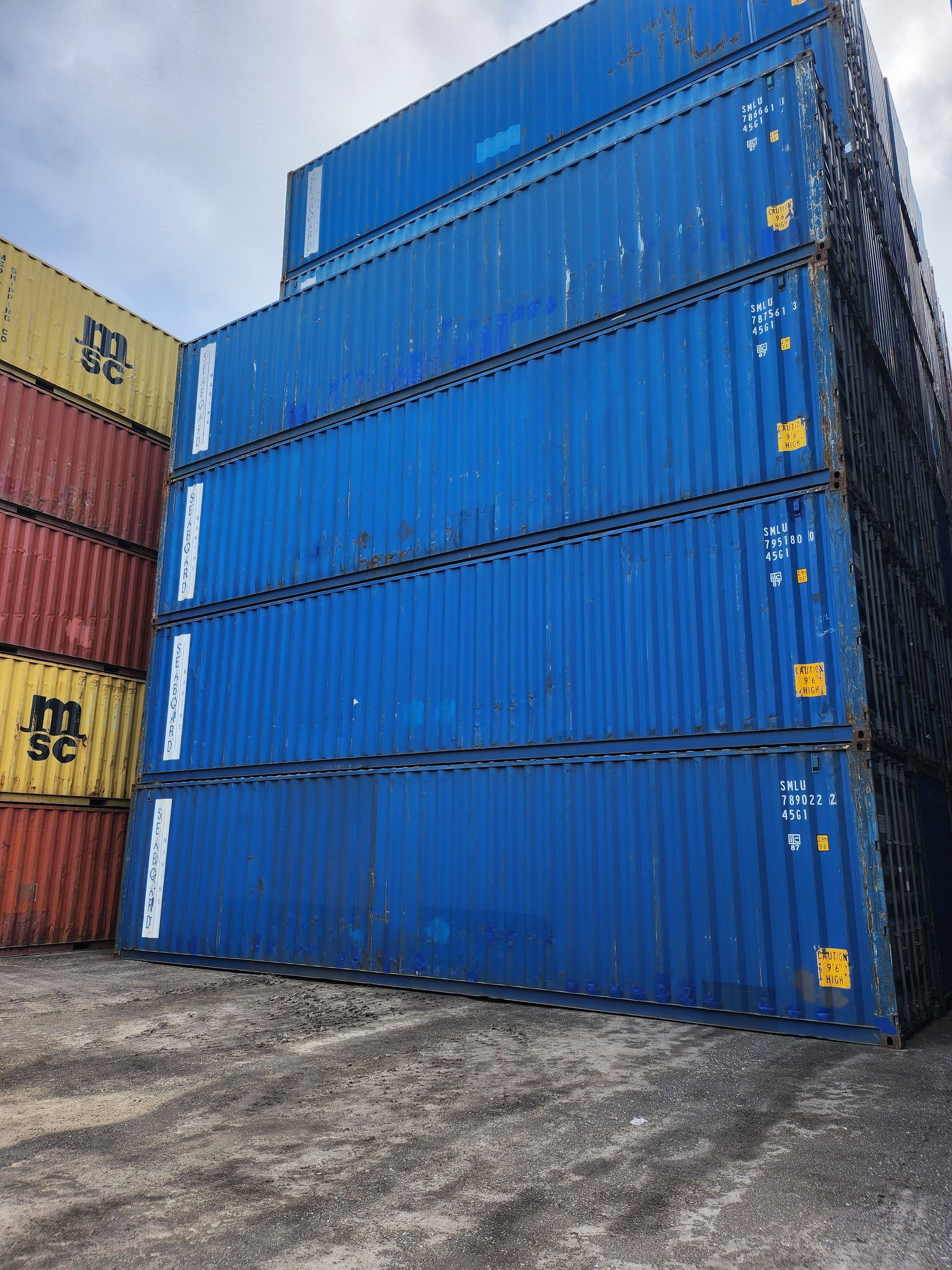 Un tas de conteneurs d'expédition sont empilés les uns sur les autres dans un parking.