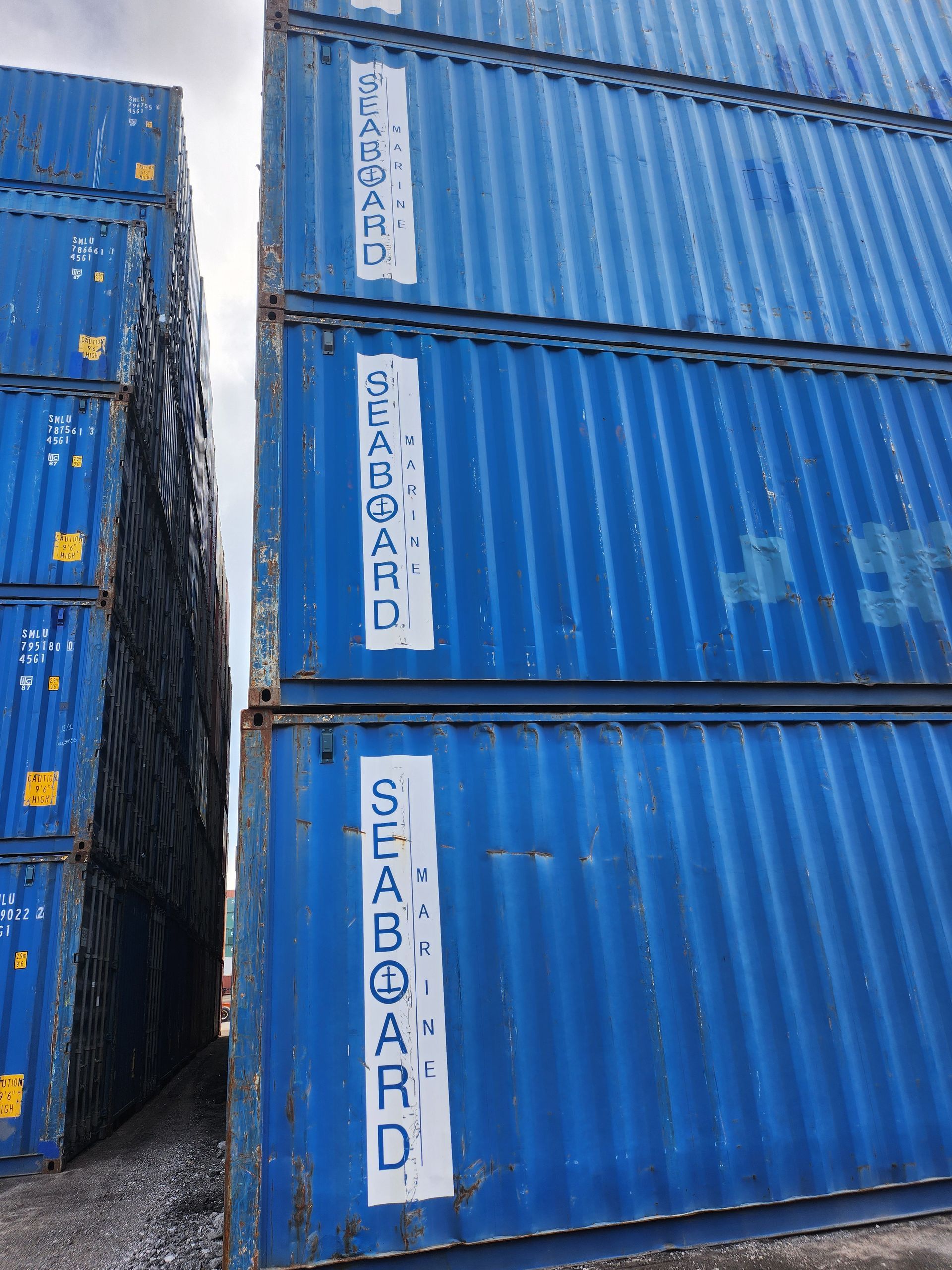 Plusieurs conteneurs maritimes bleus sont empilés les uns sur les autres