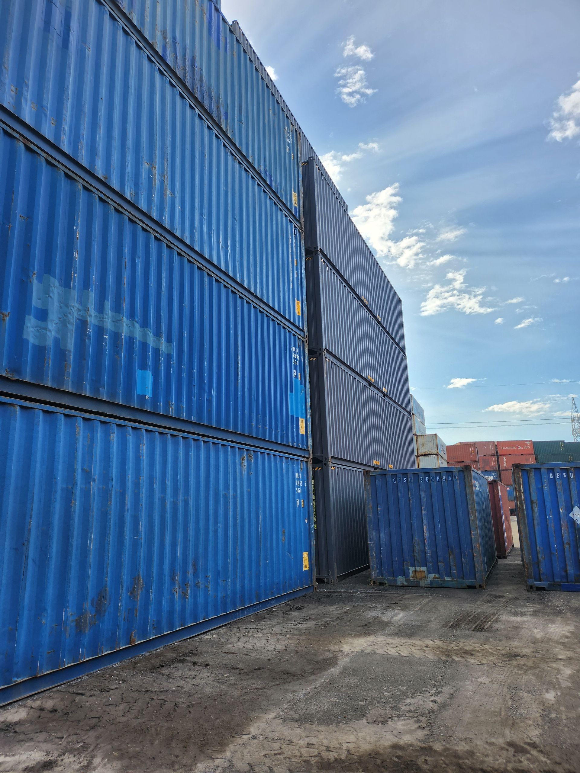 Une rangée de conteneurs d'expédition bleus empilés les uns sur les autres.