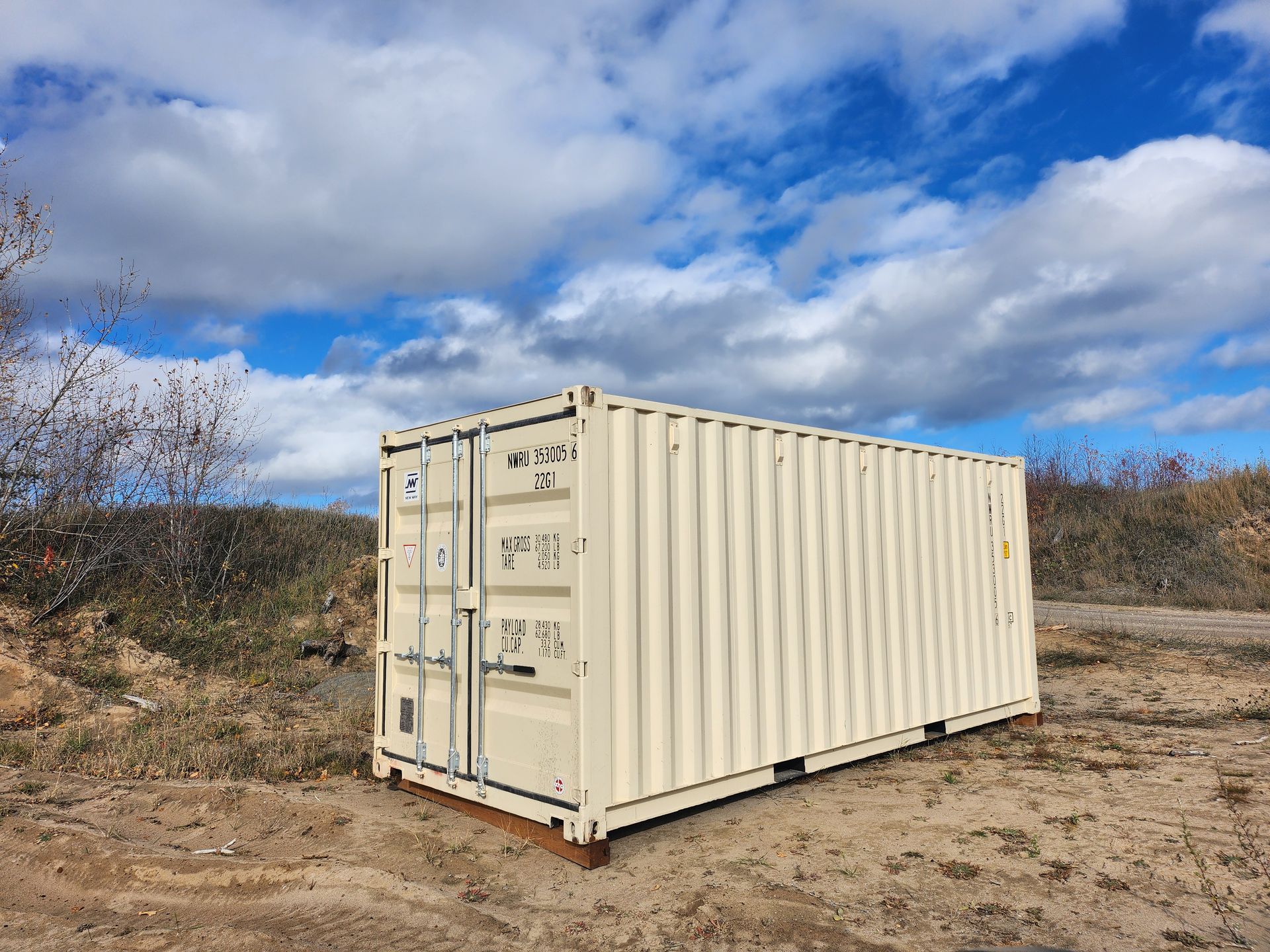 Un conteneur d'expédition blanc se trouve au milieu d'un champ de terre.