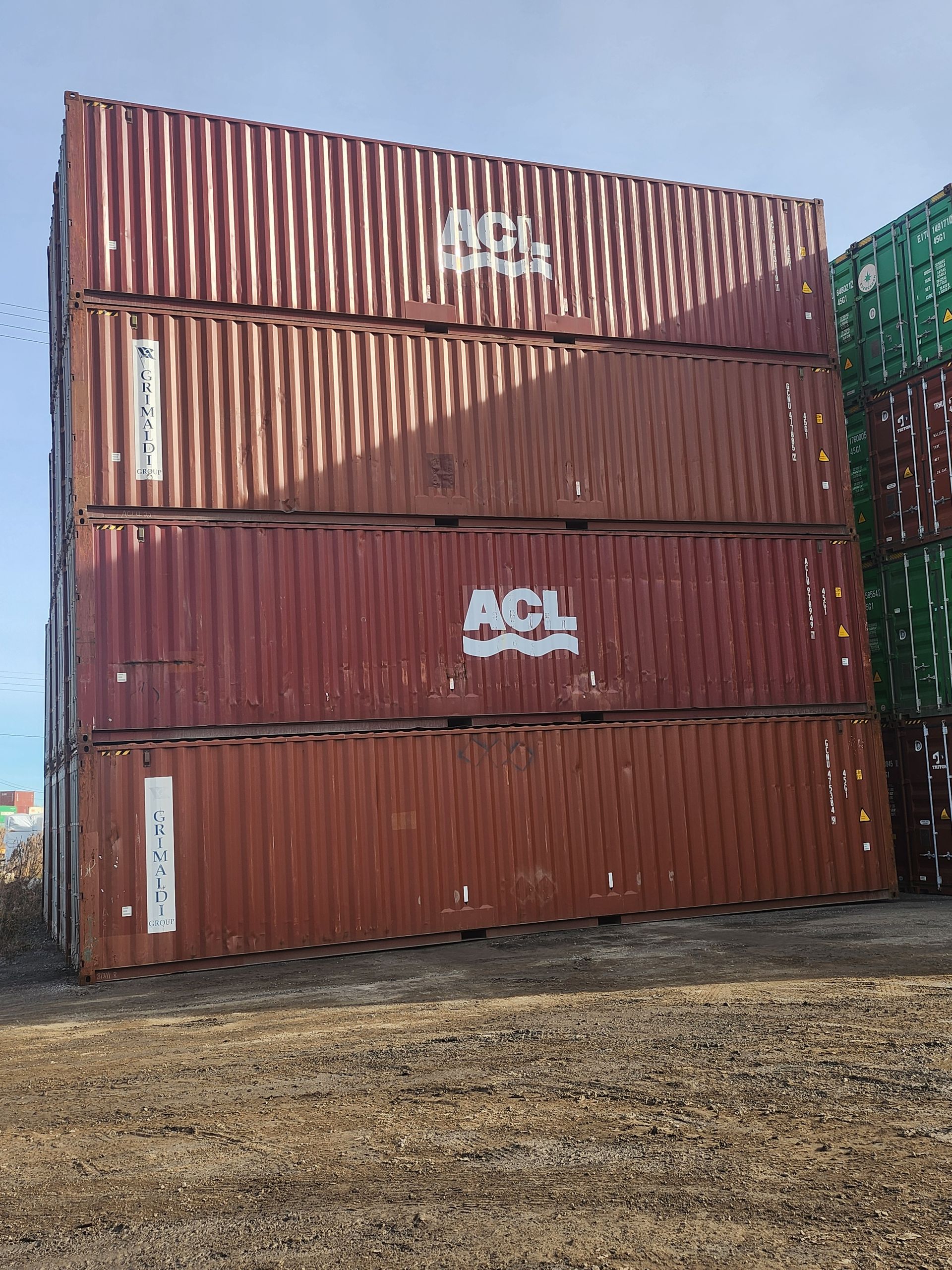 Une pile de conteneurs d'expédition posés les uns sur les autres dans un champ.