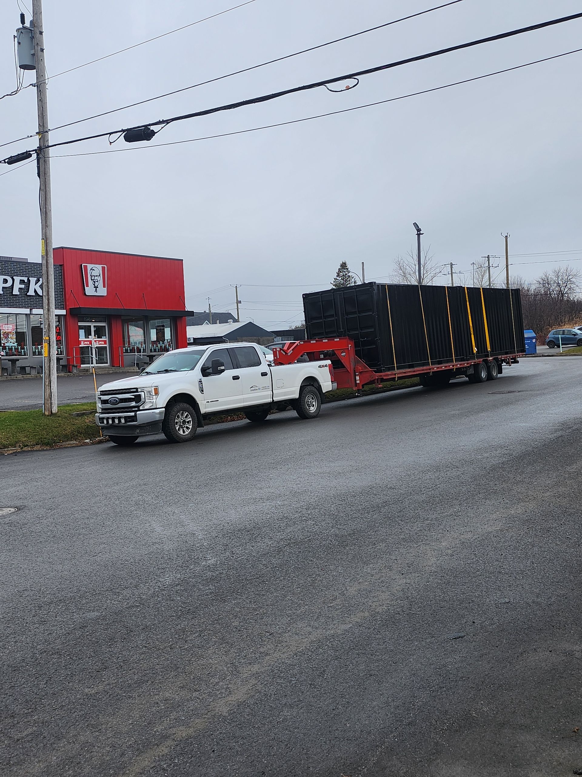Deux camions blancs sont garés sur le bord de la route.