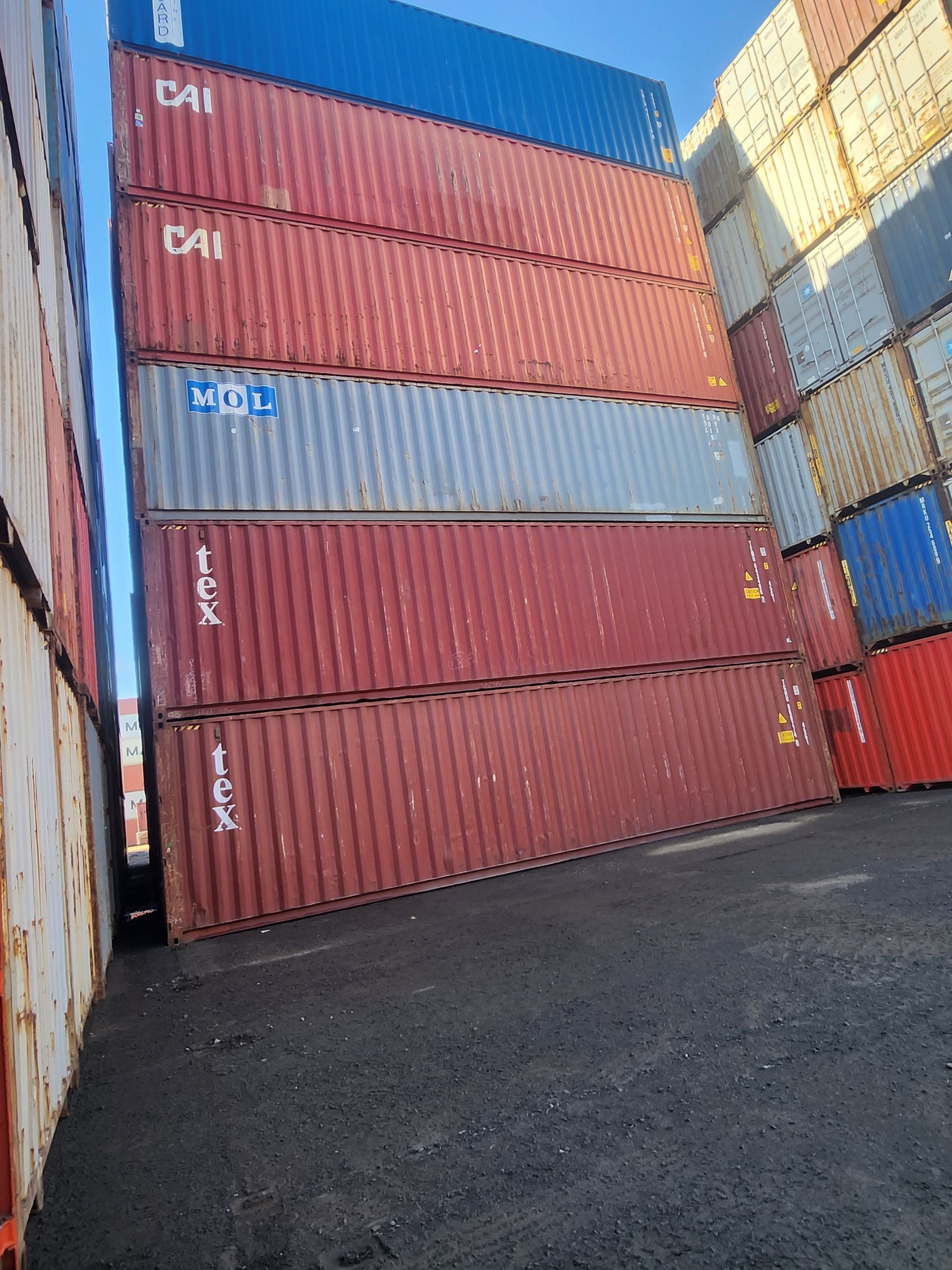 Un tas de conteneurs d'expédition sont empilés les uns sur les autres dans un parking.