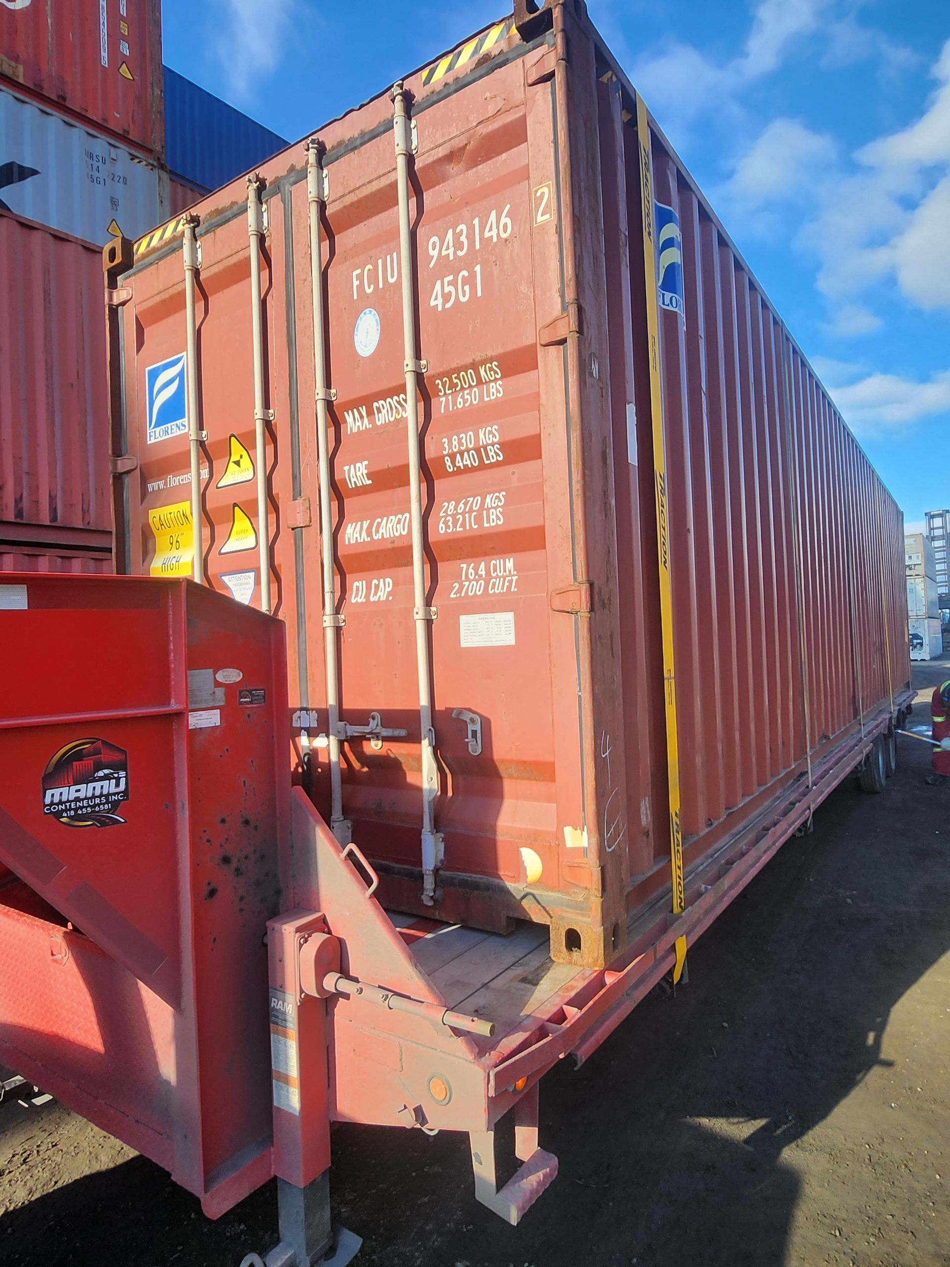 Un conteneur d'expédition rouge est posé sur une remorque.