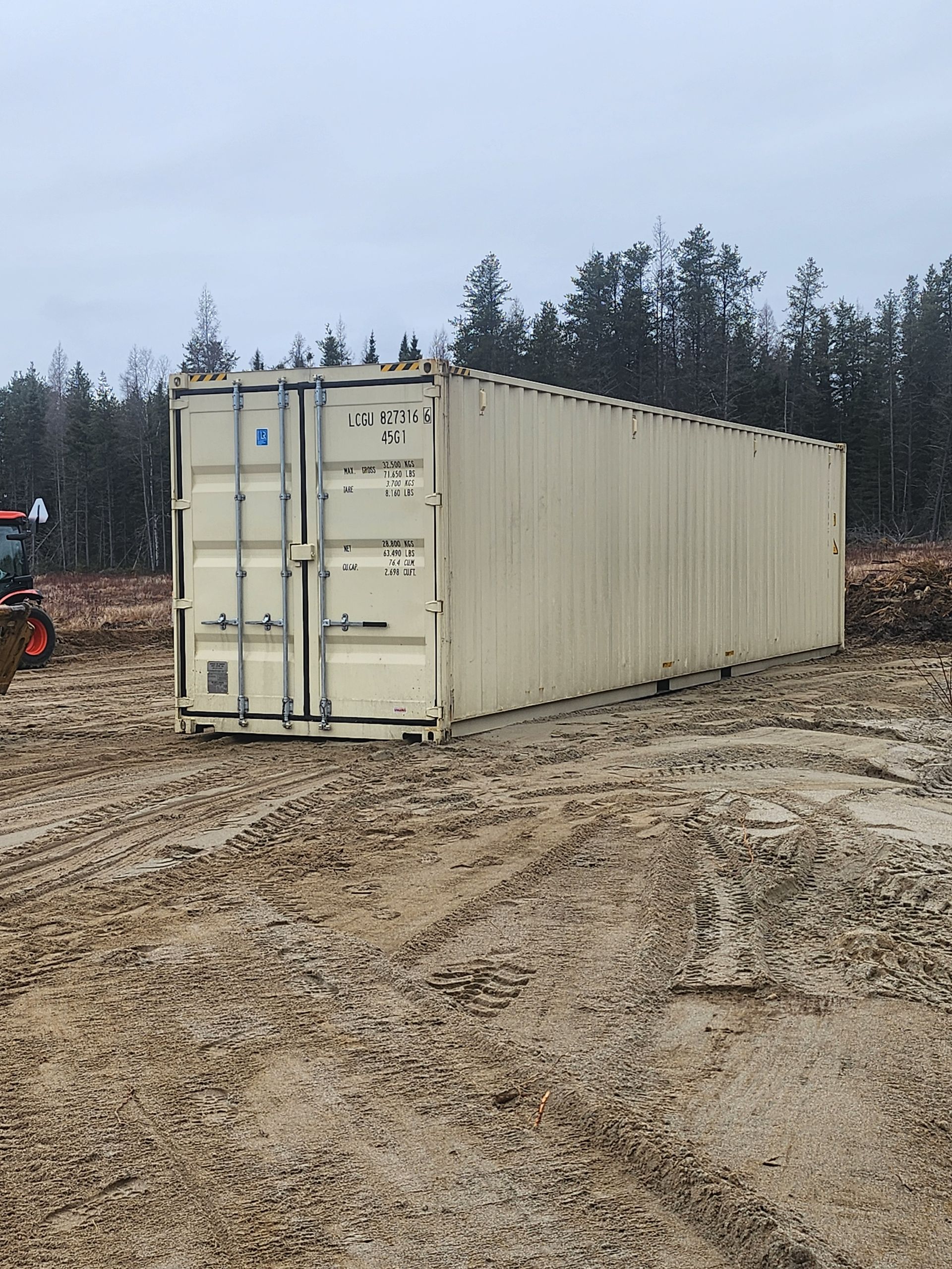 Un conteneur d'expédition se trouve au milieu d'un champ de terre.