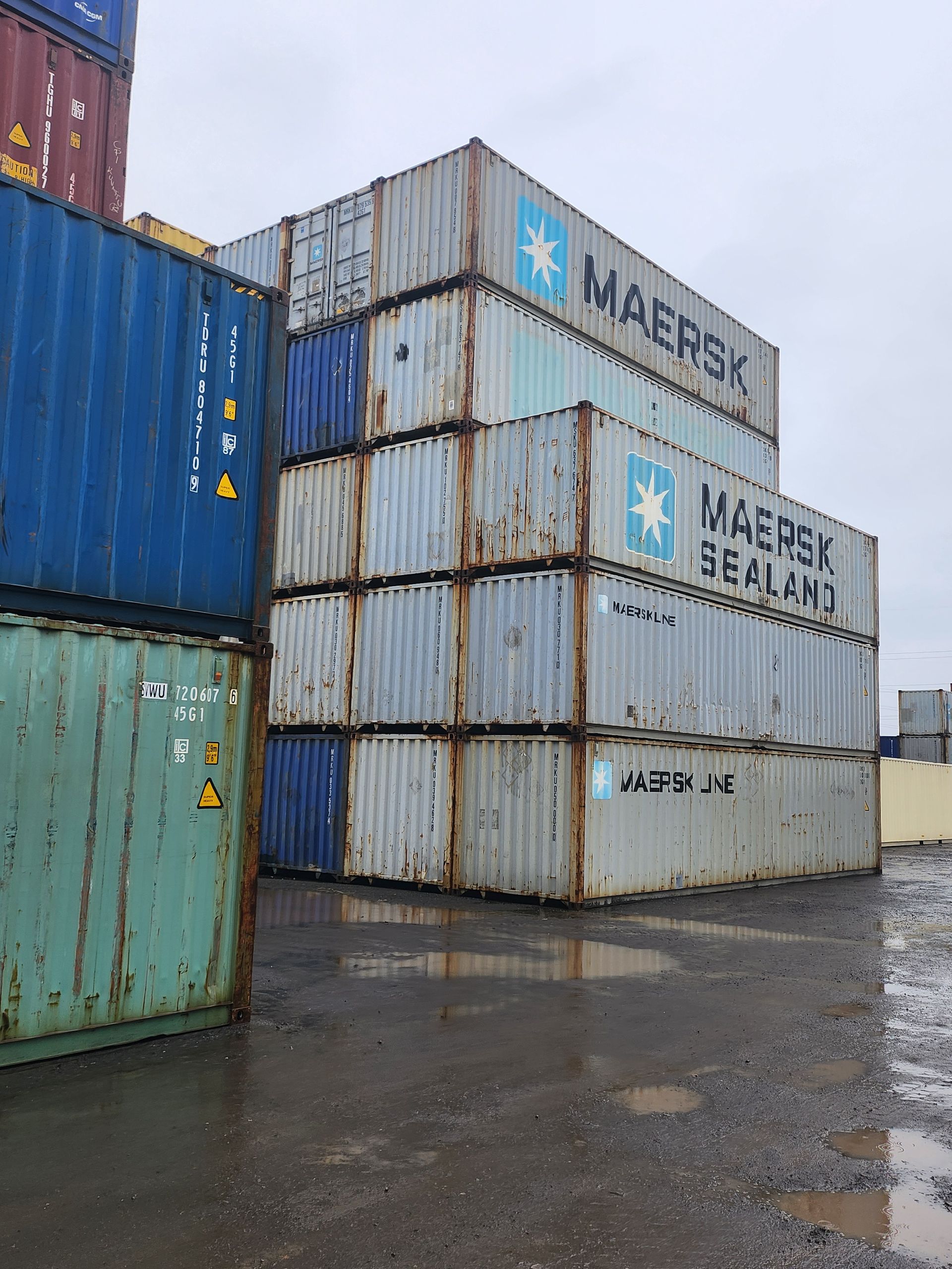 Un tas de conteneurs d'expédition sont empilés les uns sur les autres.