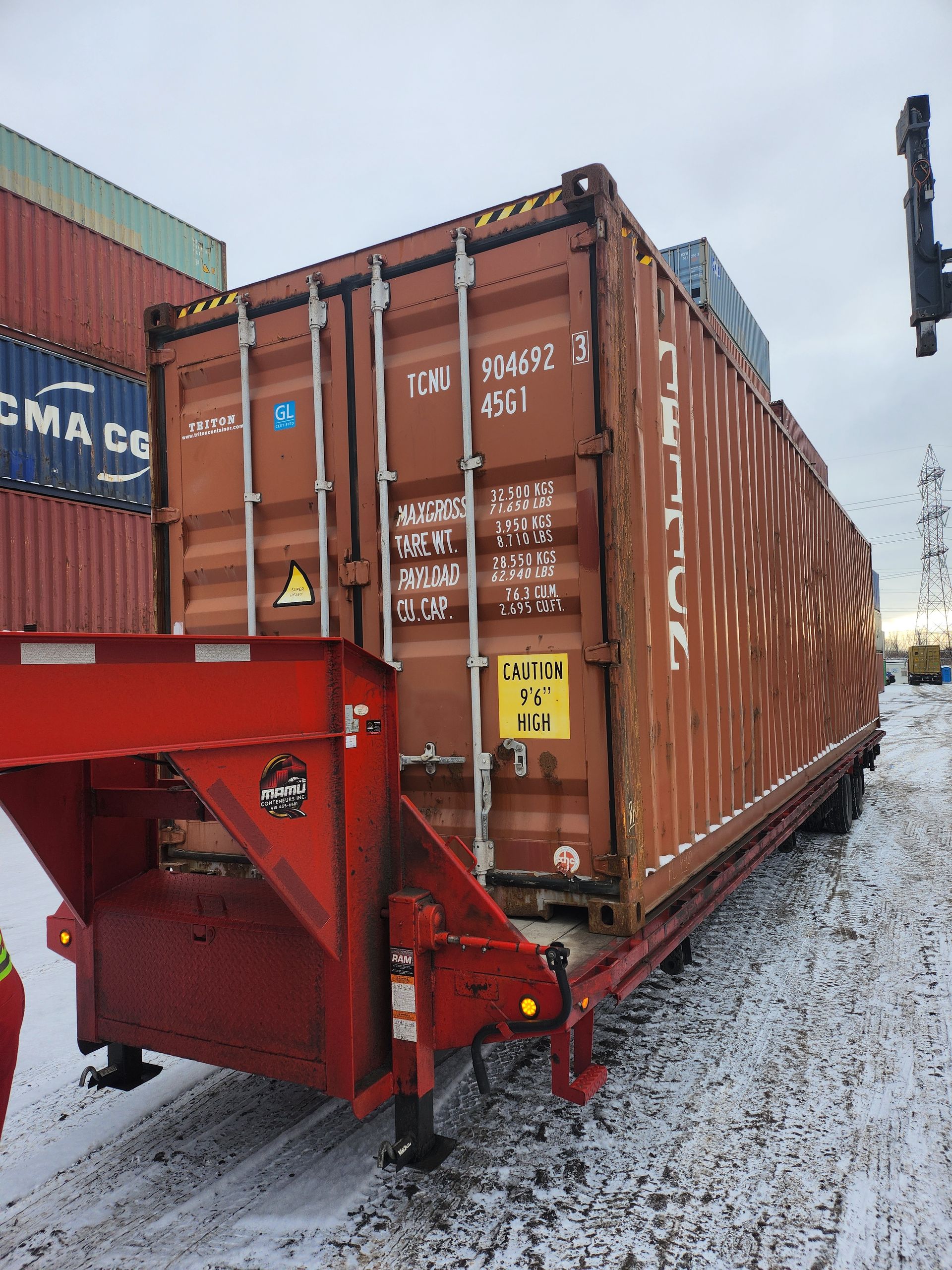 Un conteneur d'expédition est tiré par une remorque dans la neige.