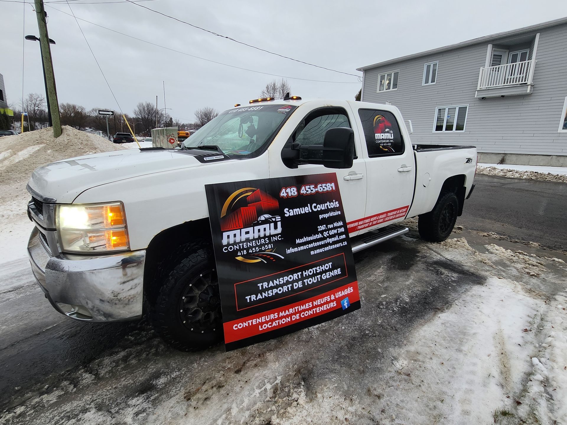 Un camion blanc est garé dans la neige avec un panneau sur le côté.