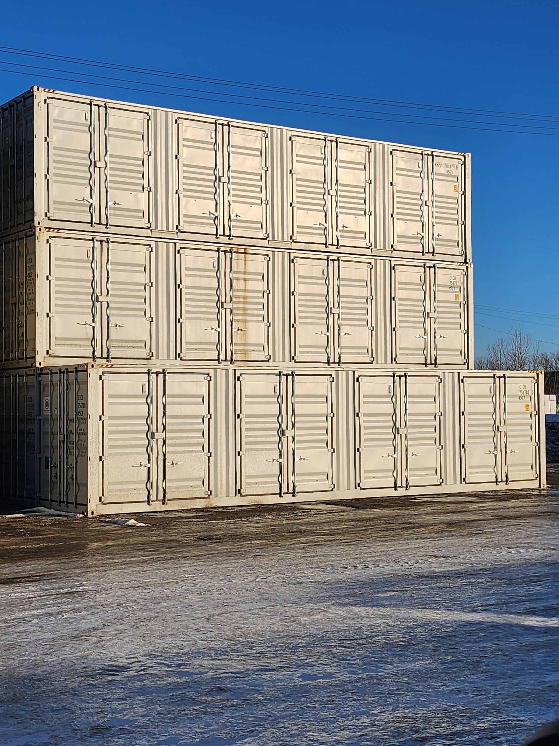 Une pile de conteneurs d'expédition posés les uns sur les autres dans un champ enneigé.