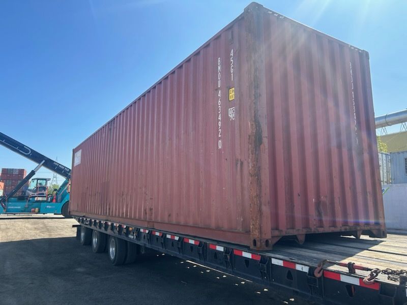 Un grand conteneur d'expédition rouge est posé sur une remorque.