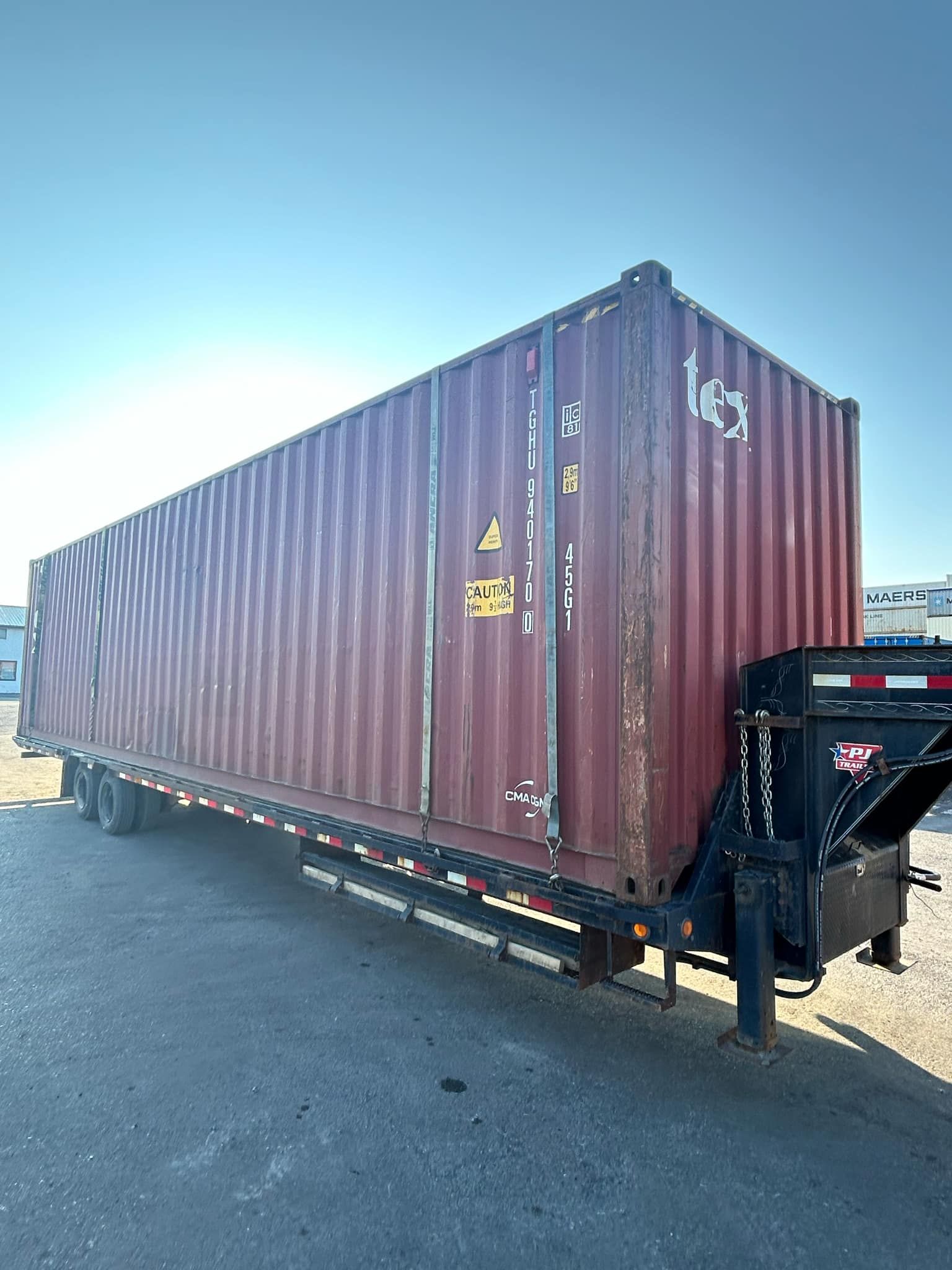 Un conteneur d'expédition rouge est posé sur une remorque.