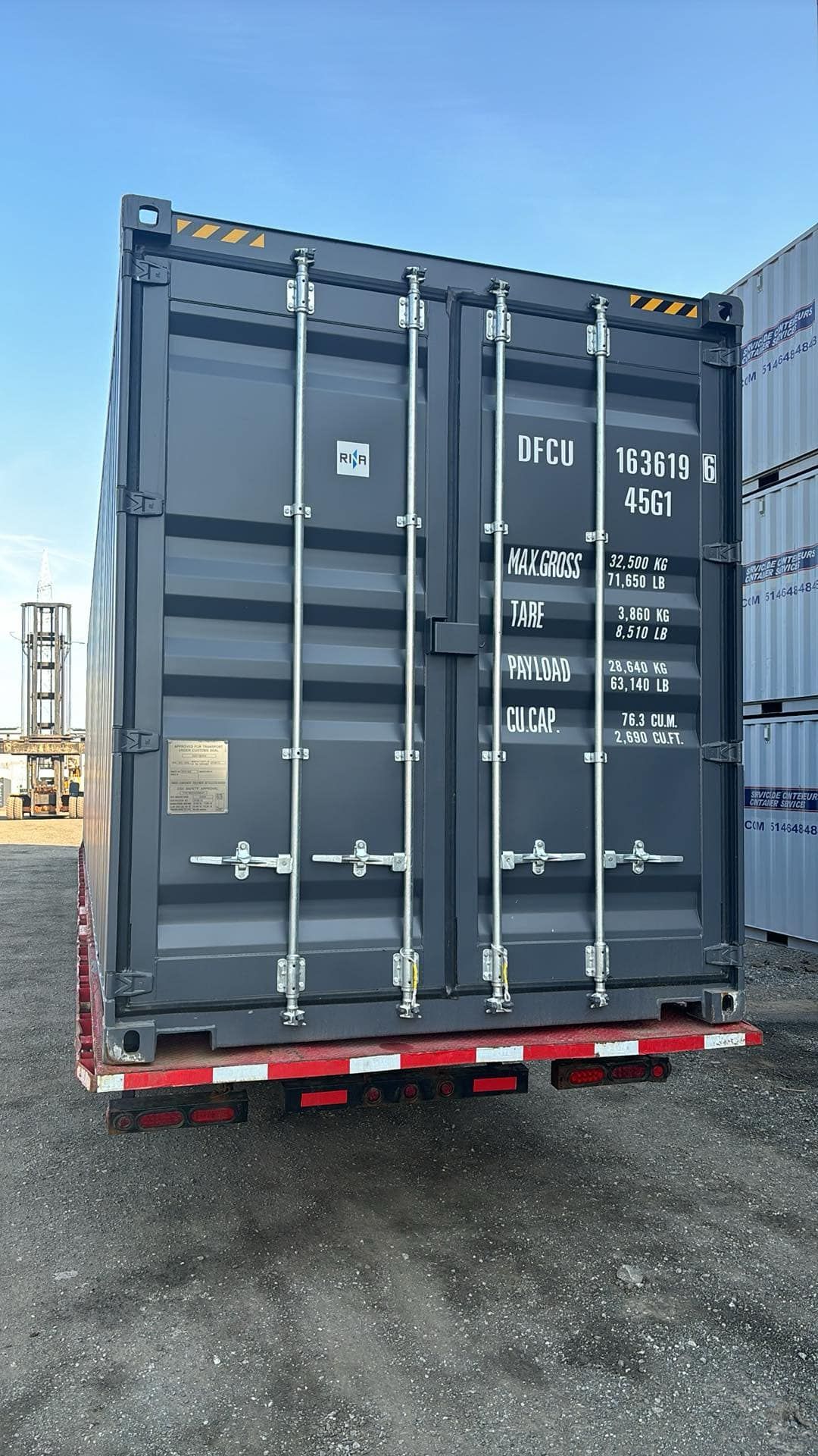 Un conteneur d'expédition noir est garé sur un parking.