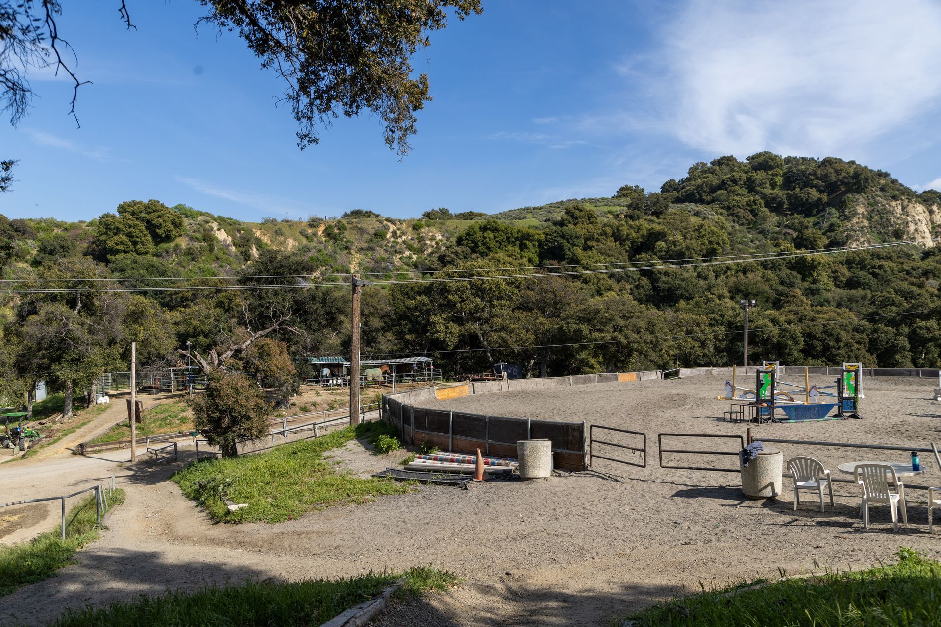 A large dirt field with a fence and trees in the background.