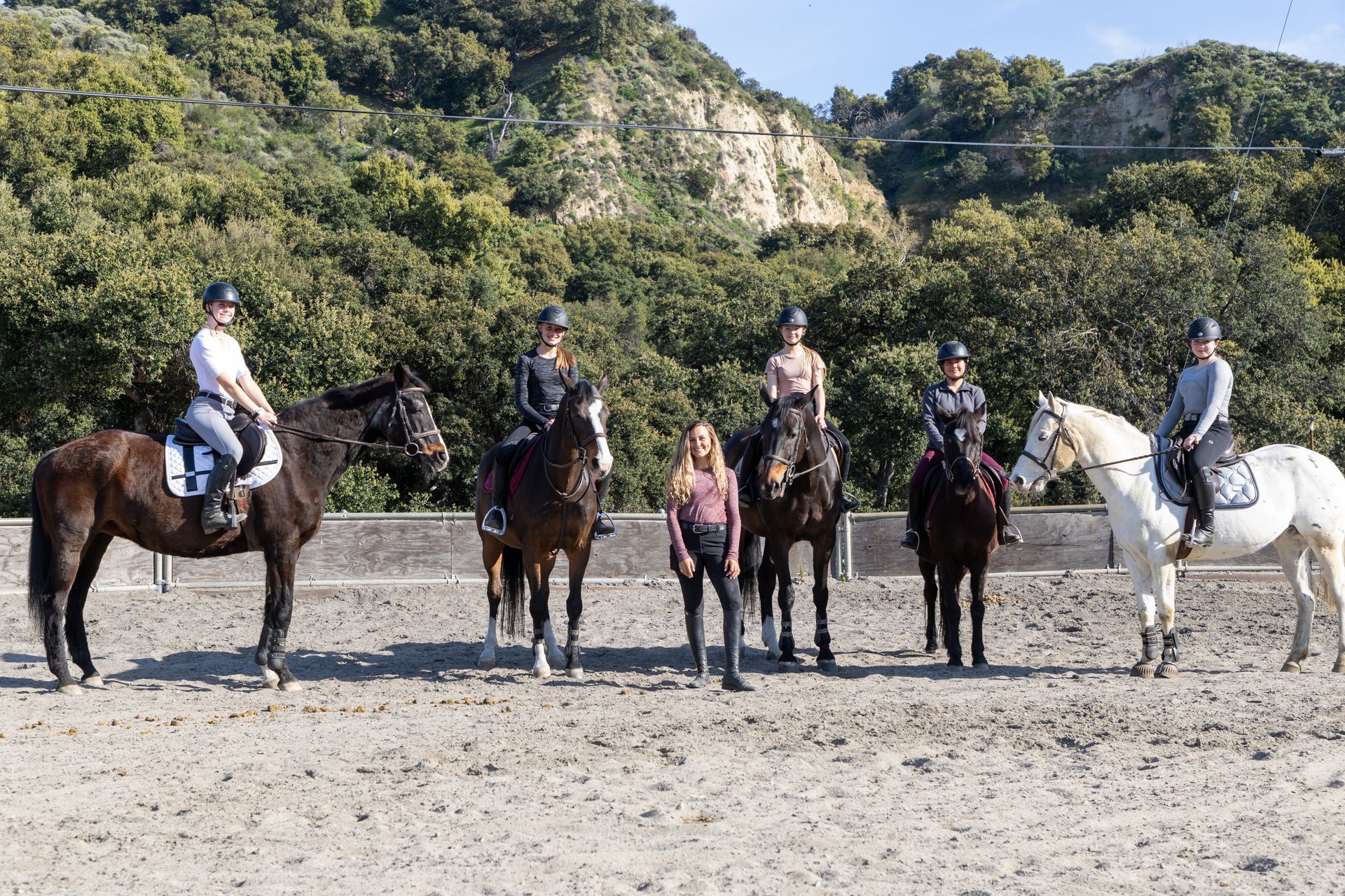 A group of people riding horses in a dirt field.