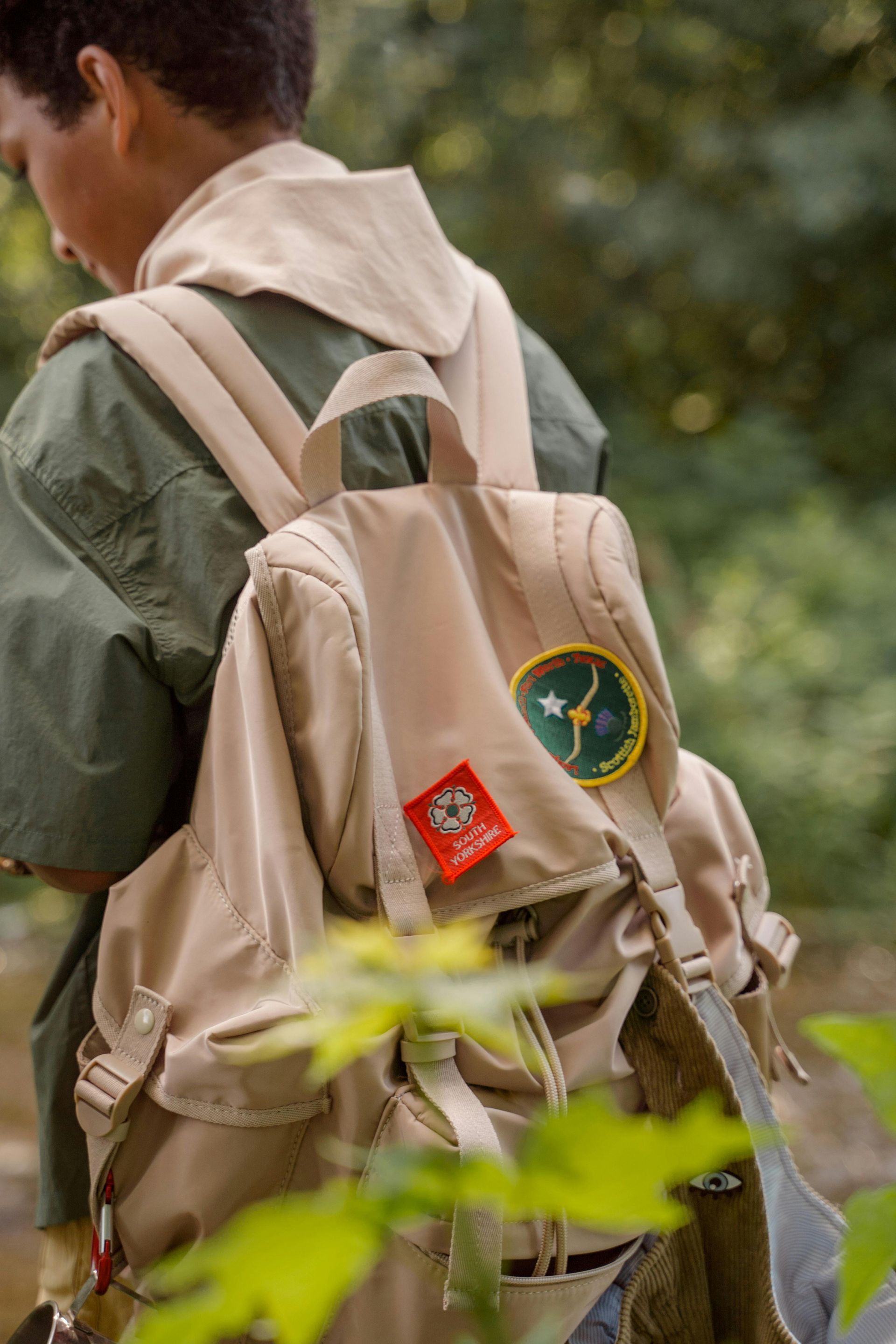 A boy is wearing a backpack with a patch on it.