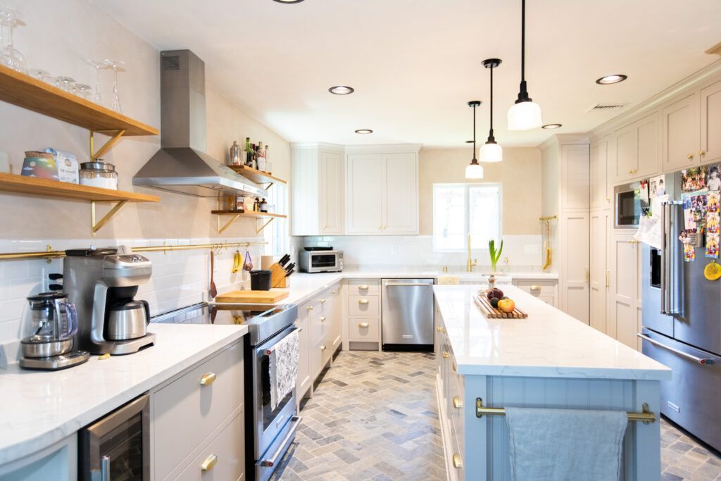 a kitchen with white cabinets , stainless steel appliances , and a large island .