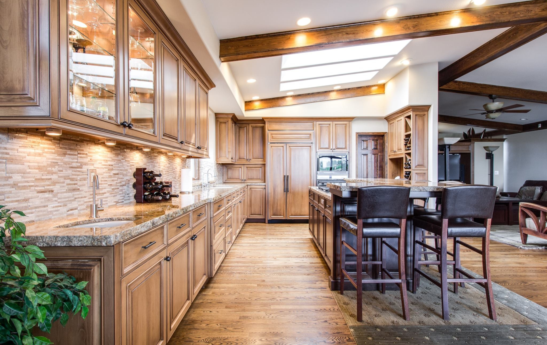 a kitchen with wooden cabinets , granite counter tops , and stools .