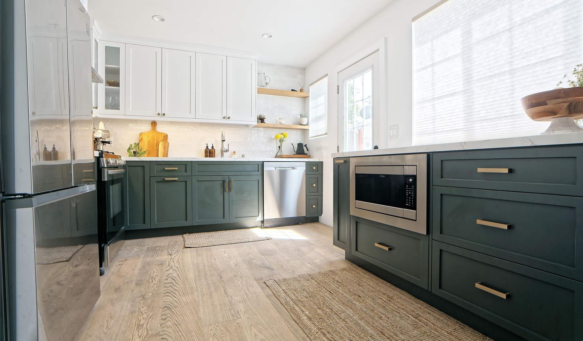 a kitchen with green cabinets , white cabinets , stainless steel appliances and a rug .