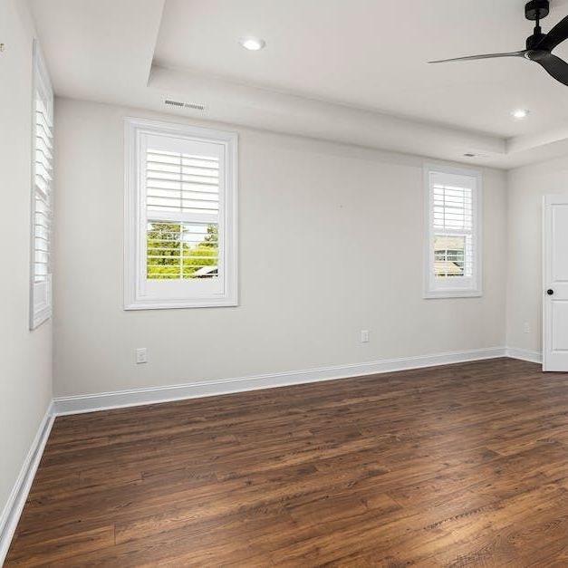 an empty bedroom with hardwood floors and a ceiling fan .