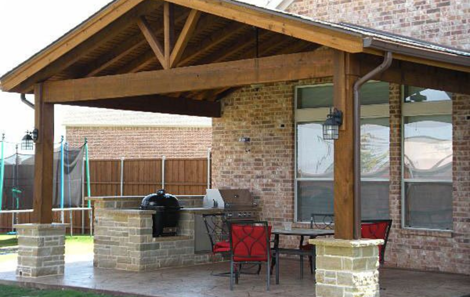 A patio with a wooden roof and a grill