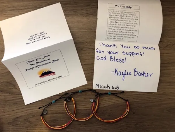 A thank you card and bracelets are on a wooden table.