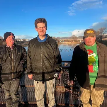Three men standing next to each other with one wearing a grinch shirt