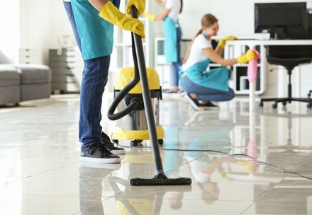 A man is using a vacuum cleaner to clean the floor in an office.