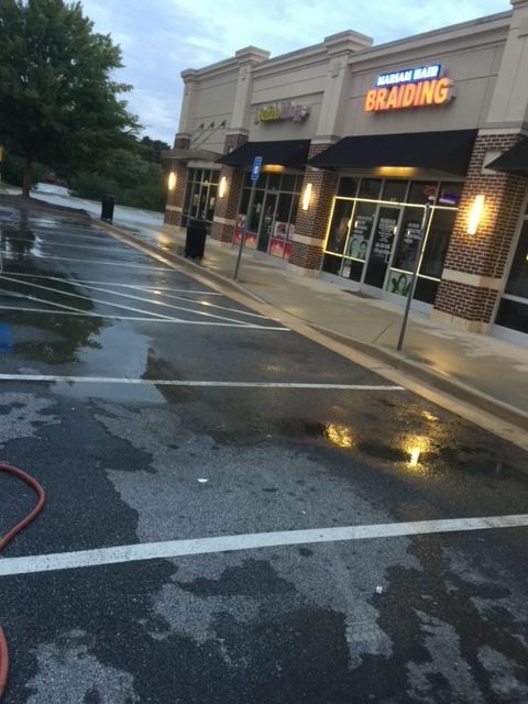 Wet parking lot in front of a strip mall with signs for 