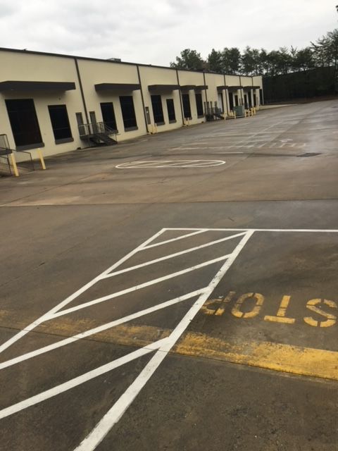 Exterior of a commercial building with loading docks and painted parking lot markings, including a stop area.