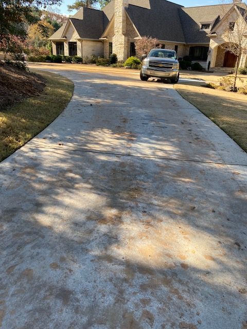 Concrete driveway leading to a large house with a truck parked in front. Shadows cast across the driveway.