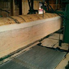 A large piece of wood is being cut by a machine.