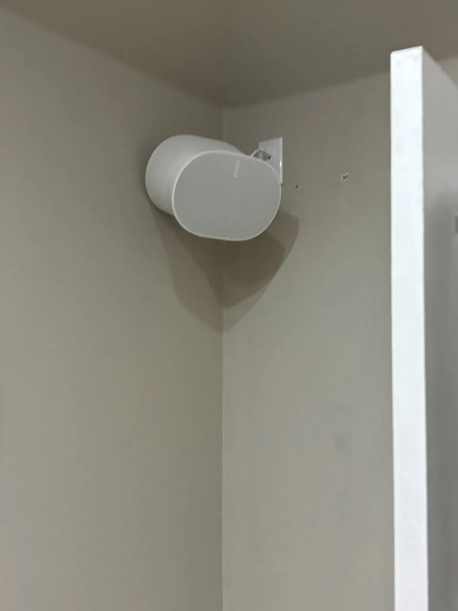 A white Wi-Fi router mounted on a beige wall in the corner of a room.
