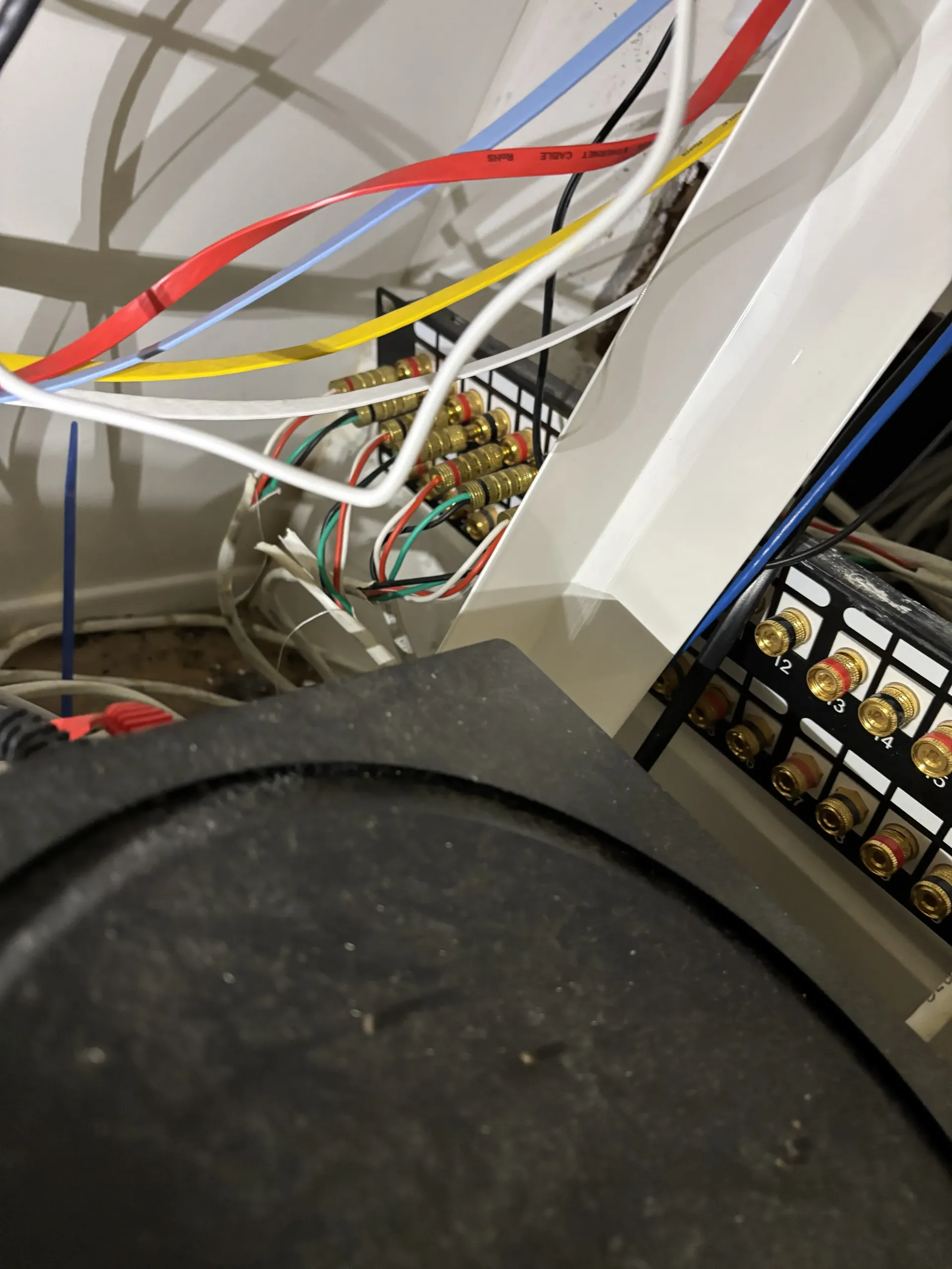 A tangle of colorful wiring connected to a patch panel behind a black equipment console.