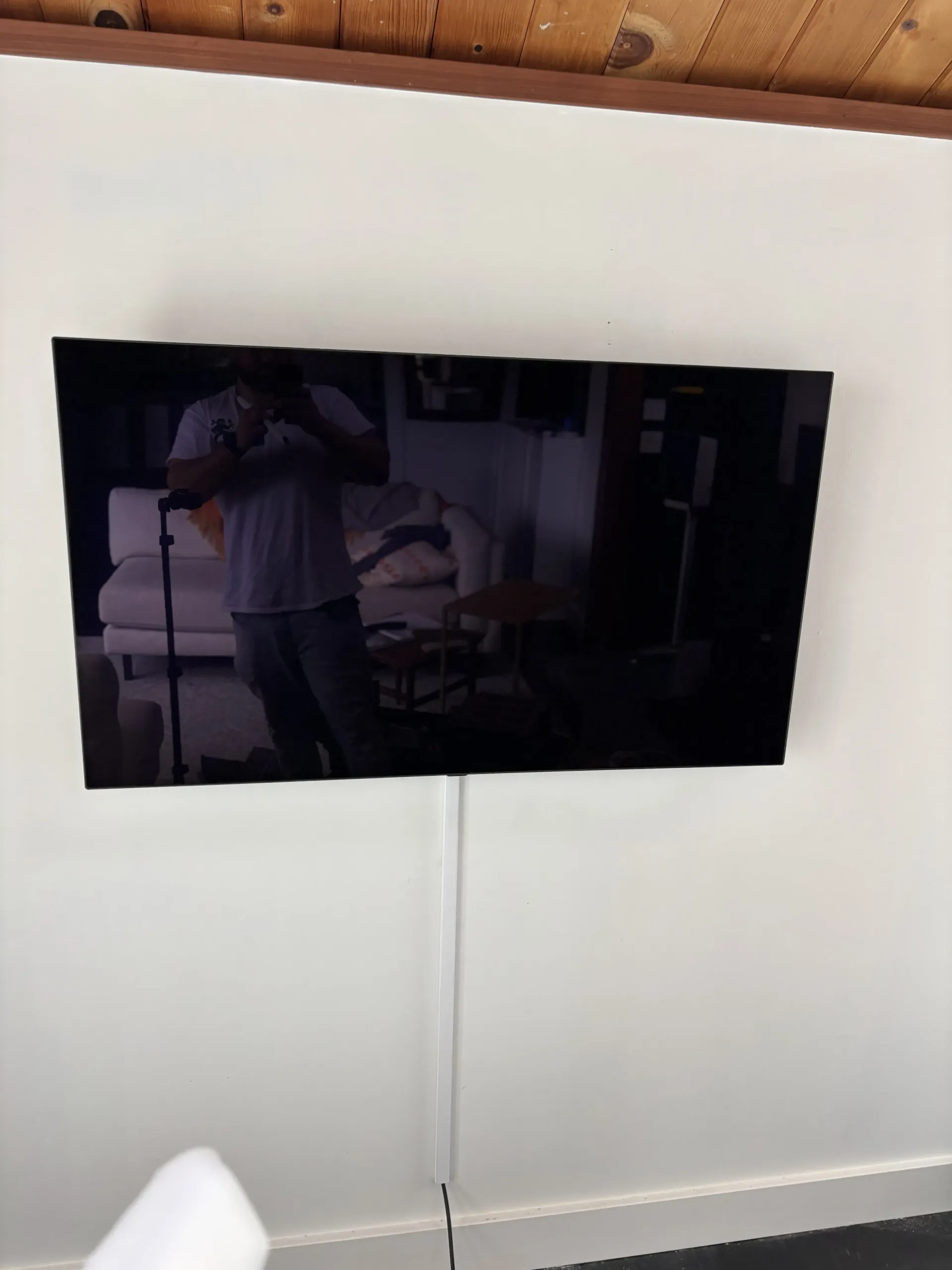 A flat-screen television mounted on a white wall with a white cable cover running vertically beneath it.