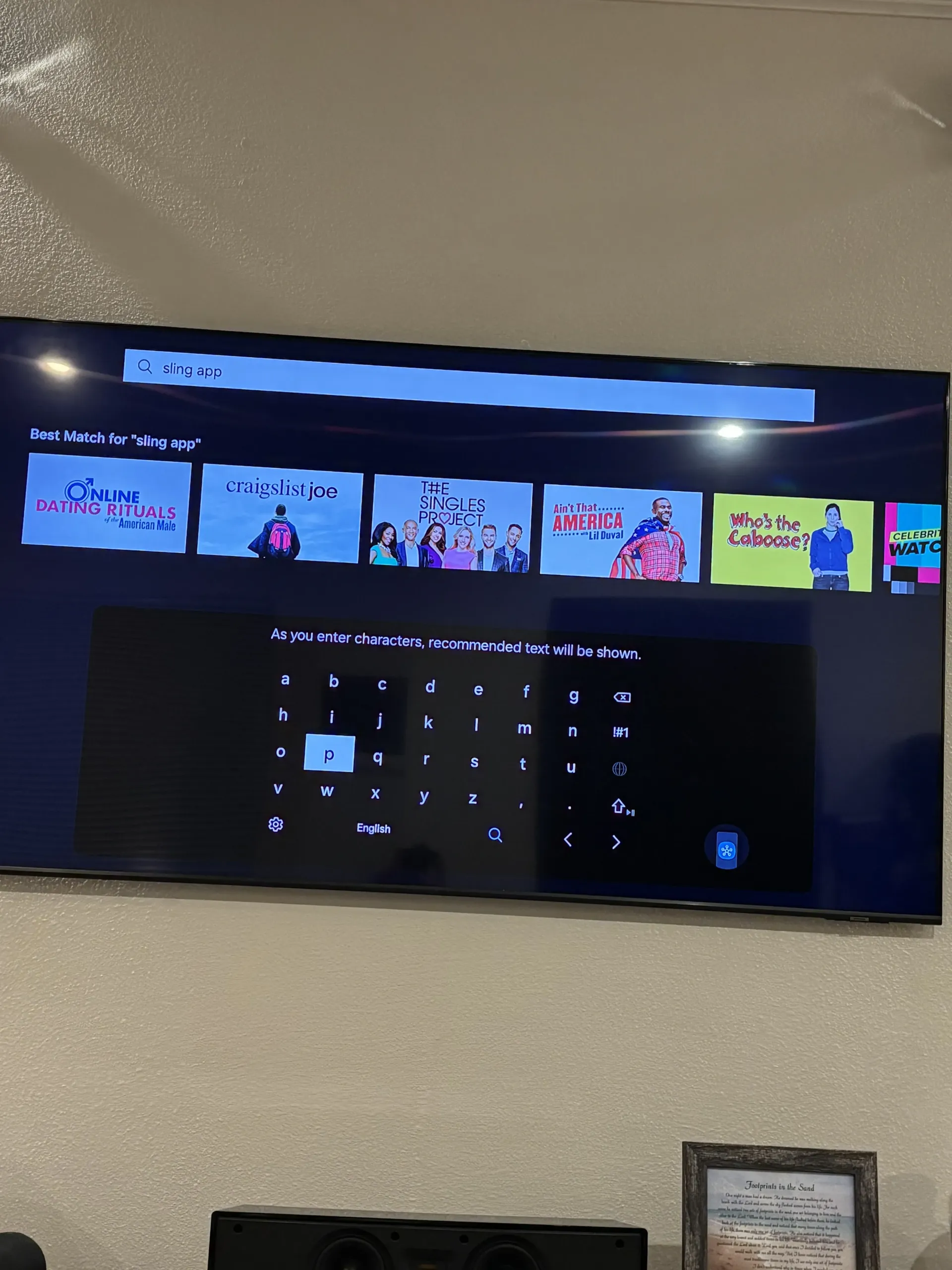A television screen displays a search interface with a digital keyboard and a row of suggested movie and show thumbnails.