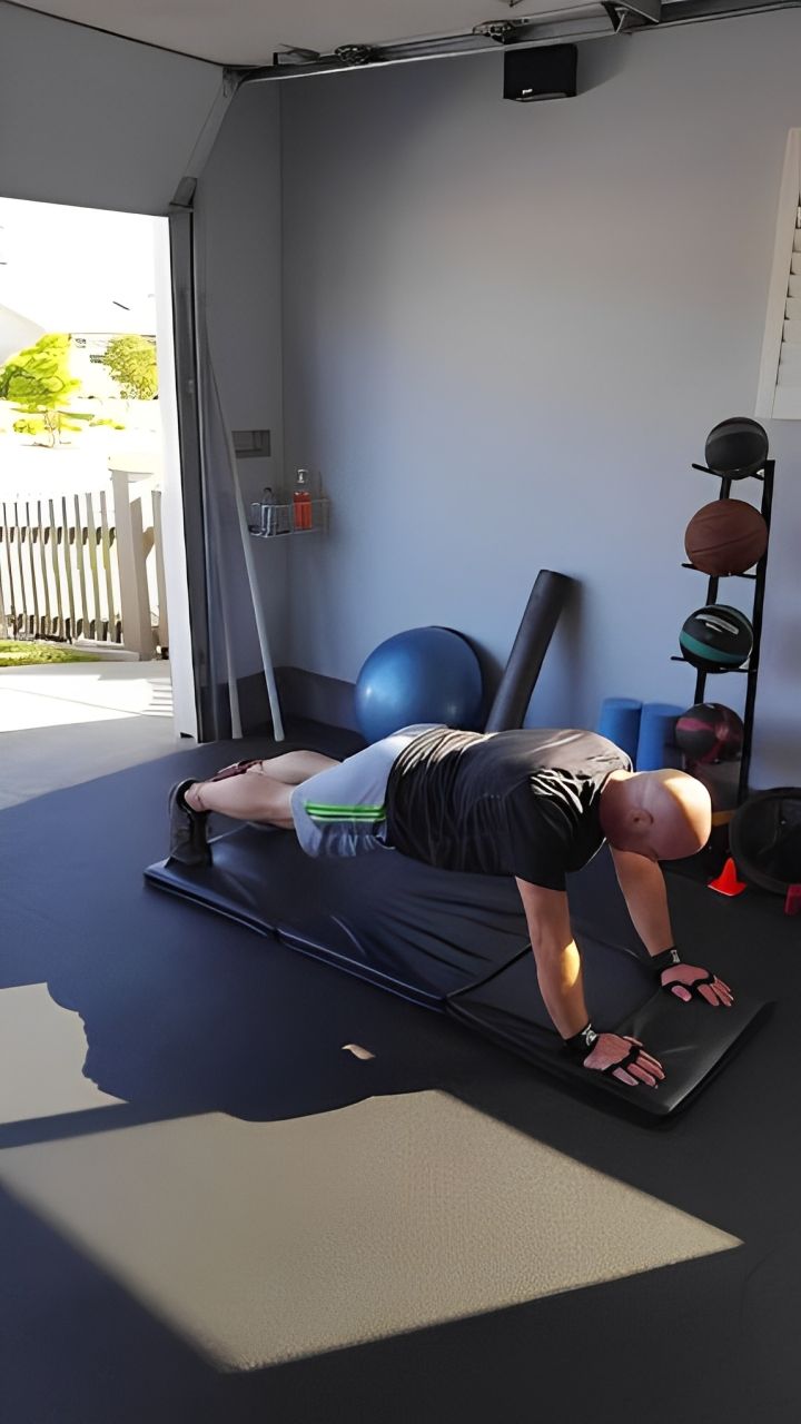 A man is doing push ups on a mat in a gym.