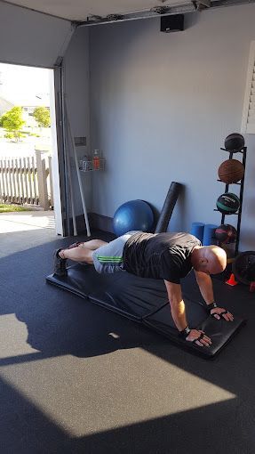 A man is doing push ups on a mat in a garage.