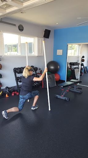 A woman is holding a pole in a gym.